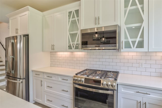 kitchen featuring stainless steel appliances, white cabinets, and tasteful backsplash