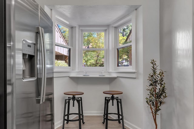 interior space featuring light wood-type flooring, stainless steel fridge, and a textured ceiling