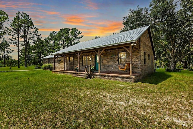 exterior space featuring covered porch and a yard