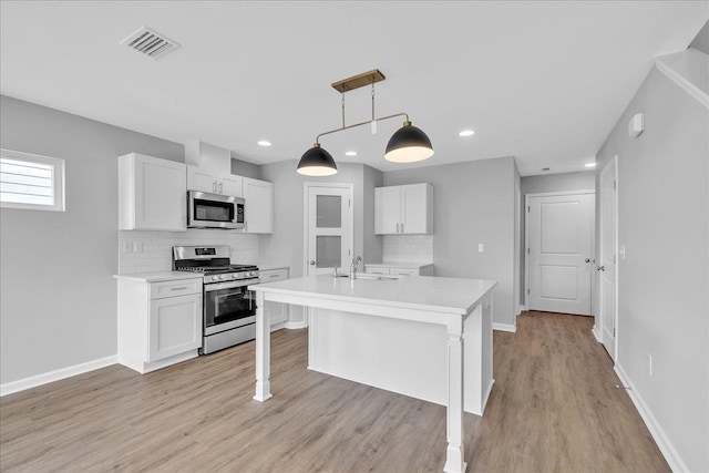 kitchen with visible vents, light countertops, stainless steel appliances, white cabinetry, and a sink