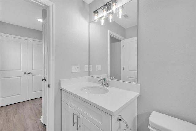 bathroom with visible vents, toilet, vanity, and wood finished floors