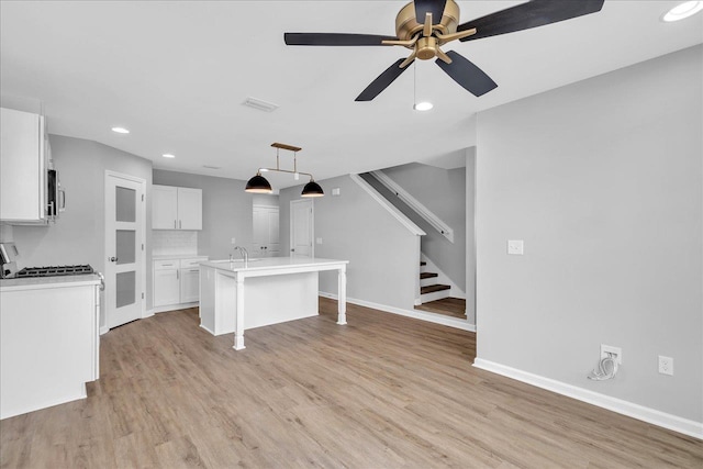 kitchen featuring white gas range, white cabinetry, a breakfast bar, and light wood-type flooring