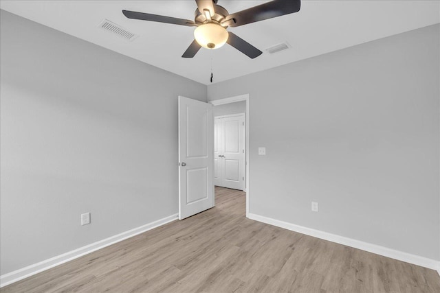 spare room with light wood finished floors, visible vents, ceiling fan, and baseboards