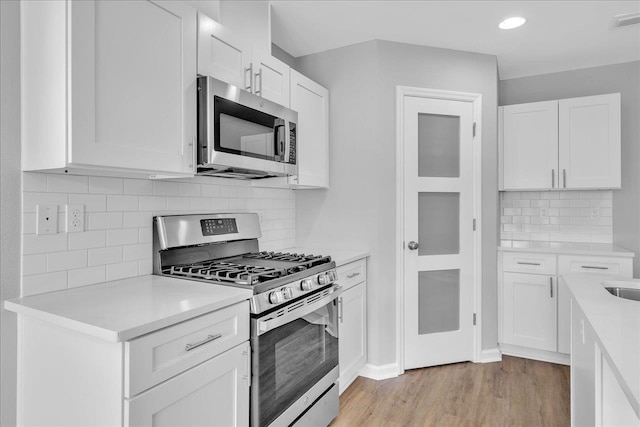 kitchen featuring visible vents, light wood-style flooring, white cabinetry, stainless steel appliances, and light countertops