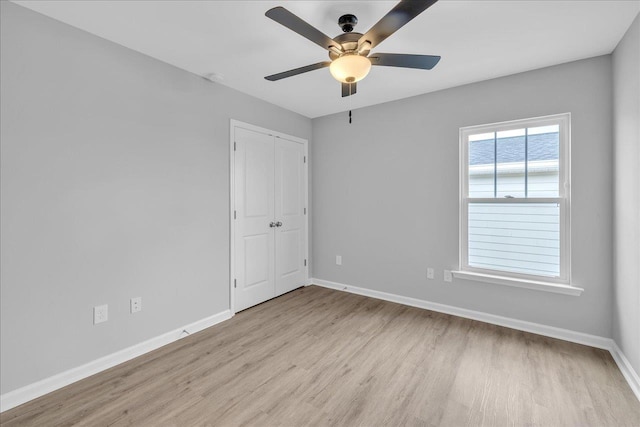 unfurnished room with a ceiling fan, wood finished floors, and baseboards