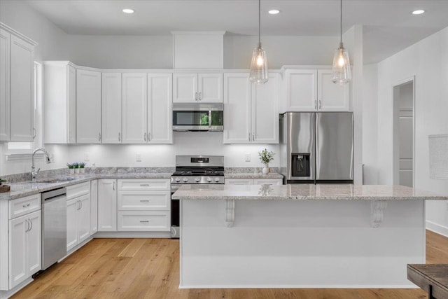 5756 Bascom Ln, Tallahassee, FL 32309 - kitchen featuring stainless steel appliances, a sink, white cabinets, a center island, and light wood-style flooring