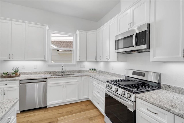 5756 Bascom Ln, Tallahassee, FL 32309 - kitchen with appliances with stainless steel finishes, a sink, white cabinets, light stone countertops, and light wood-style floors