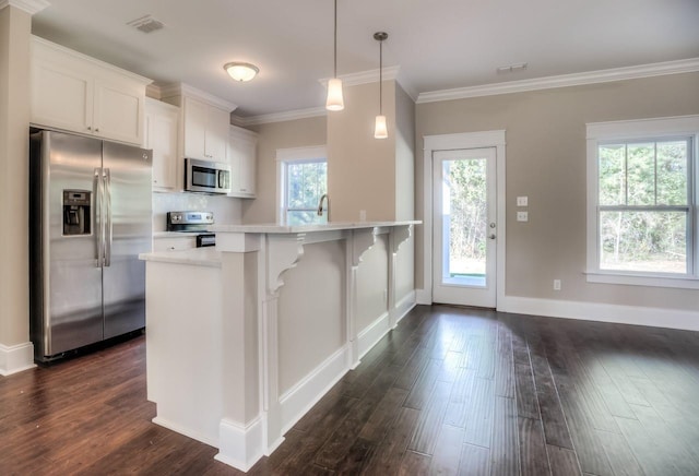 kitchen featuring dark hardwood / wood-style floors, appliances with stainless steel finishes, decorative light fixtures, and white cabinets