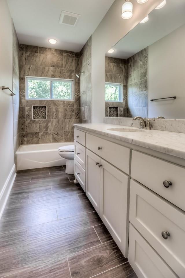 full bathroom with vanity, tiled shower / bath combo, plenty of natural light, and toilet