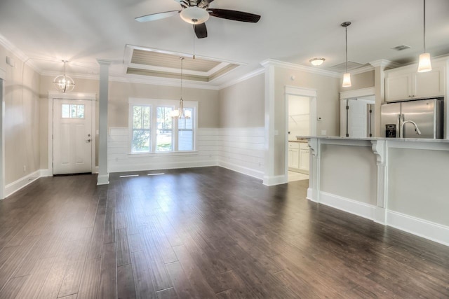 unfurnished living room with ceiling fan with notable chandelier, ornamental molding, dark hardwood / wood-style floors, and a raised ceiling