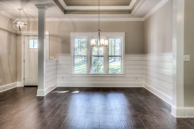 unfurnished dining area featuring dark wood-type flooring, crown molding, a chandelier, a tray ceiling, and decorative columns