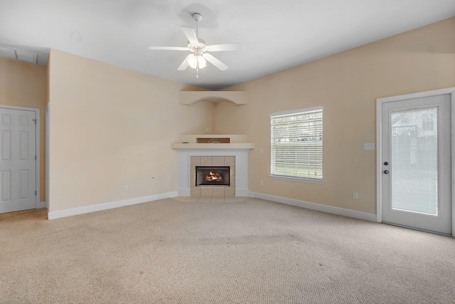 unfurnished living room featuring a tiled fireplace, light colored carpet, and ceiling fan