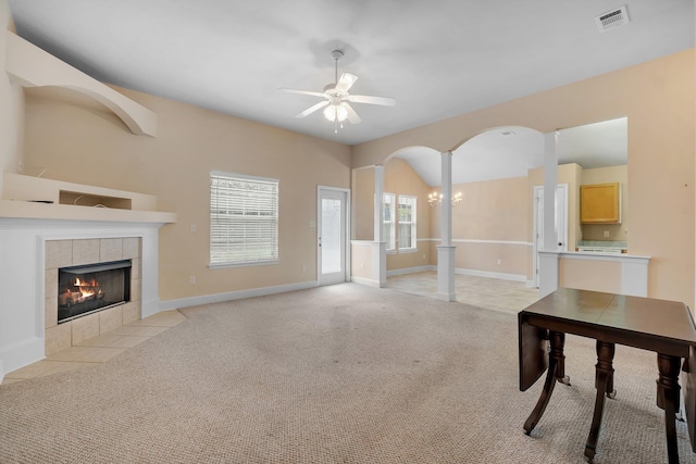 unfurnished living room with a tile fireplace, ceiling fan with notable chandelier, and light colored carpet