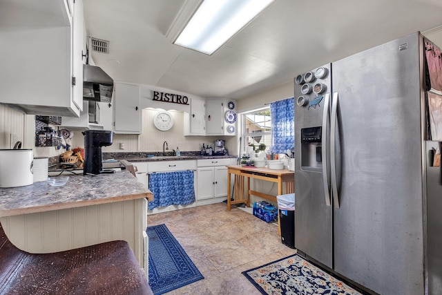 kitchen with white cabinets, wall chimney exhaust hood, sink, and stainless steel fridge