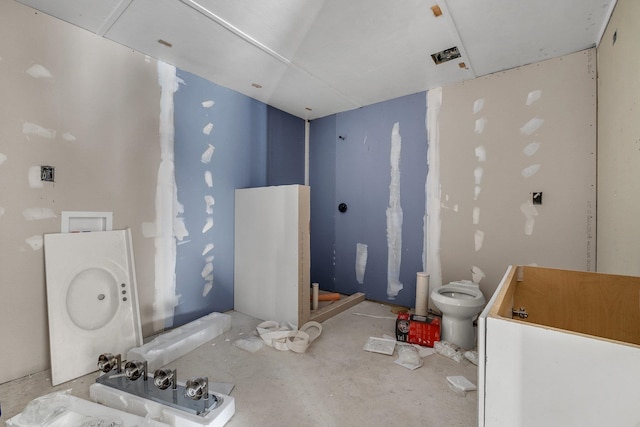 bathroom featuring concrete floors, toilet, and washer / clothes dryer