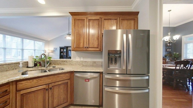 kitchen with sink, light stone counters, a chandelier, ornamental molding, and appliances with stainless steel finishes