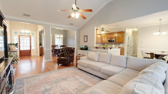 living room with ceiling fan with notable chandelier, high vaulted ceiling, ornamental molding, and light hardwood / wood-style floors