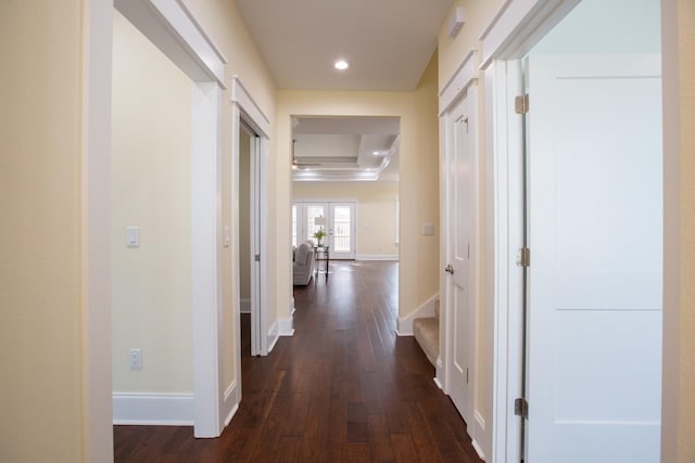 corridor with dark wood-type flooring and a raised ceiling