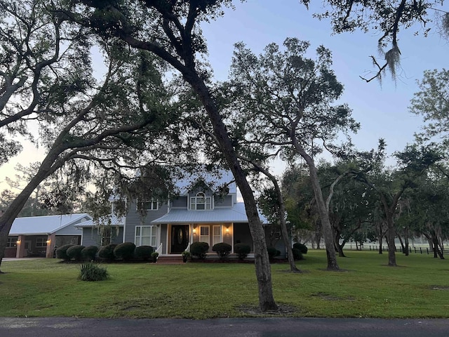 traditional home featuring covered porch, metal roof, and a front yard