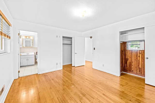 1106 Richardson Rd, Tallahassee, FL 32301 - unfurnished bedroom featuring two closets, baseboards, visible vents, and light wood-type flooring