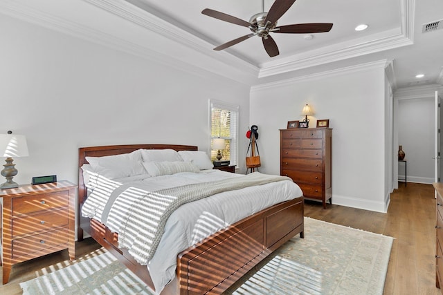 bedroom with a tray ceiling, ceiling fan, crown molding, and hardwood / wood-style flooring