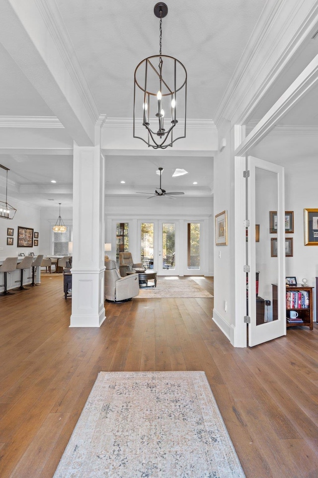 entryway with wood-type flooring, decorative columns, ceiling fan, and crown molding