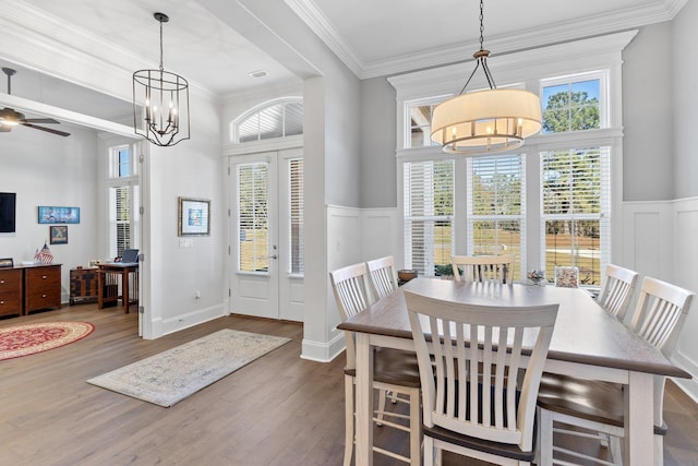 dining area featuring french doors, dark wood-type flooring, ceiling fan with notable chandelier, and ornamental molding