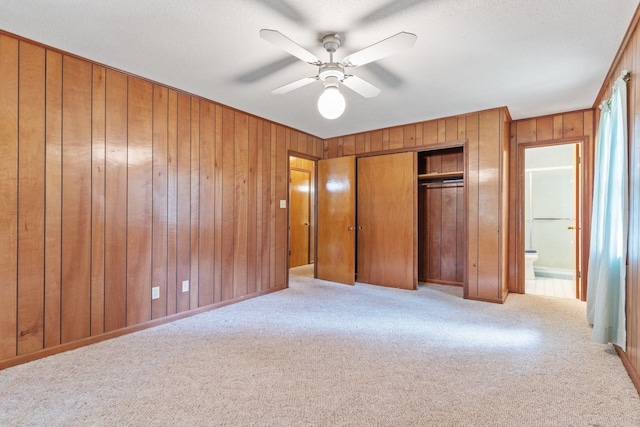 unfurnished bedroom featuring wood walls, ceiling fan, and light carpet