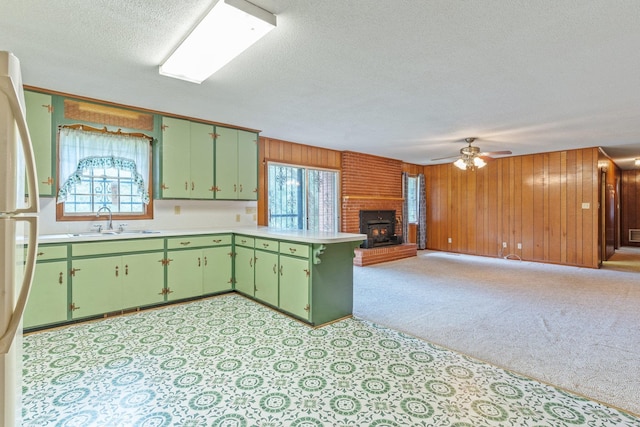 kitchen with wood walls, a textured ceiling, sink, and kitchen peninsula