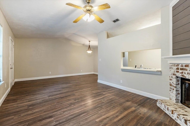 unfurnished living room with a brick fireplace, vaulted ceiling, dark hardwood / wood-style floors, and ceiling fan