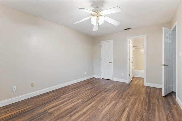 unfurnished bedroom with dark wood-type flooring, a closet, ceiling fan, and ensuite bath