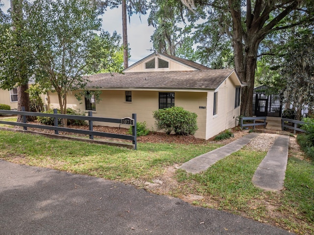 view of side of home featuring fence and roof with shingles