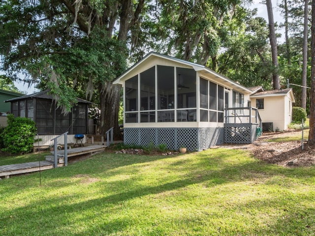 back of property featuring a sunroom, a lawn, an outbuilding, and a storage unit