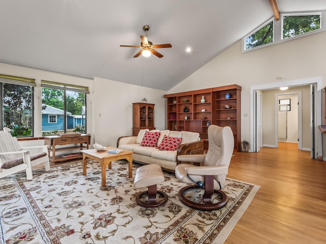 living area featuring light wood-style floors, a ceiling fan, high vaulted ceiling, and beamed ceiling