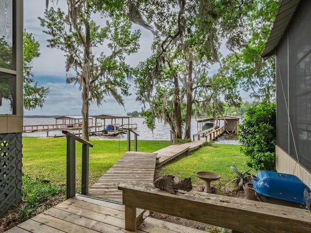 view of dock featuring a water view, boat lift, and a yard