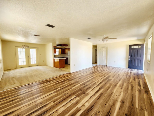 unfurnished living room featuring light wood-style floors, visible vents, and a textured ceiling