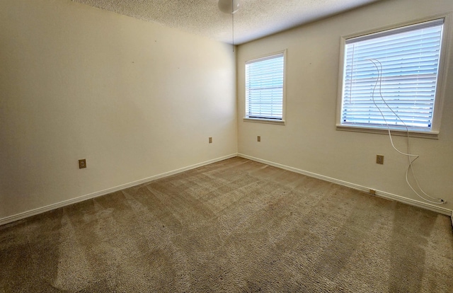 carpeted empty room with a textured ceiling and baseboards