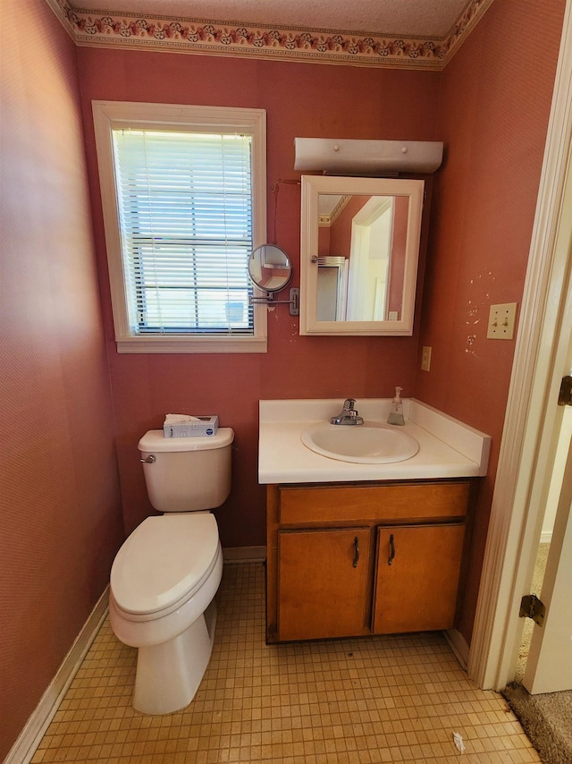 half bath featuring baseboards, vanity, and toilet