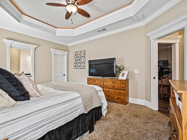 carpeted bedroom with a tray ceiling, ornamental molding, and ceiling fan