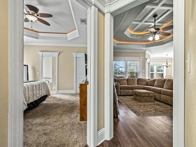 hallway with a notable chandelier, crown molding, a tray ceiling, and dark hardwood / wood-style floors