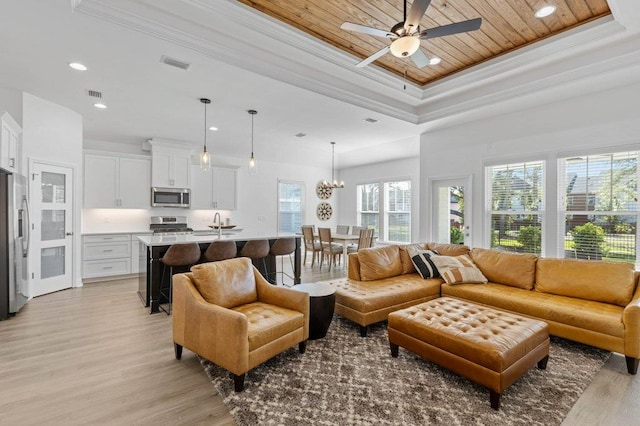 living room with a raised ceiling, wooden ceiling, ornamental molding, and light hardwood / wood-style flooring