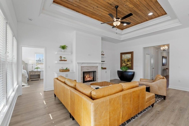 living room featuring wooden ceiling, ceiling fan, crown molding, a tray ceiling, and light wood-type flooring