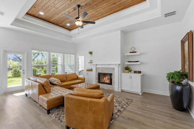 living room featuring a fireplace, wood ceiling, a high ceiling, a tray ceiling, and light hardwood / wood-style flooring