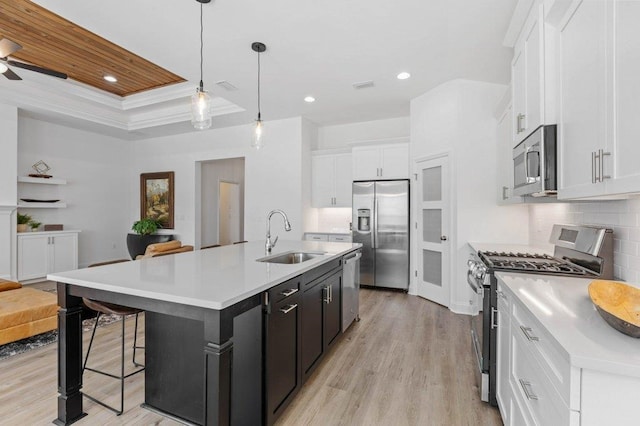 kitchen featuring stainless steel appliances, pendant lighting, sink, and a kitchen island with sink