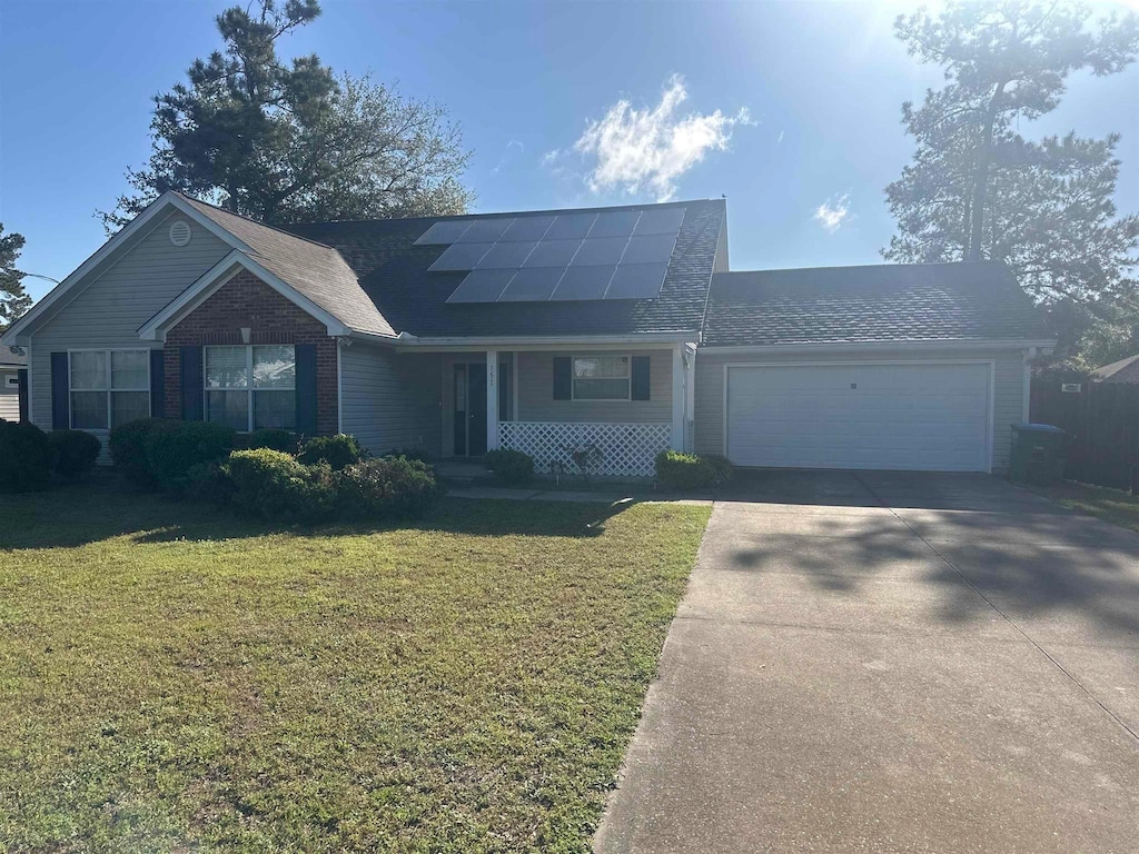 view of front of property featuring driveway, an attached garage, solar panels, and a front lawn