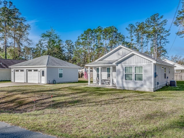 view of front of home with central air condition unit, a detached garage, a front yard, board and batten siding, and covered porch