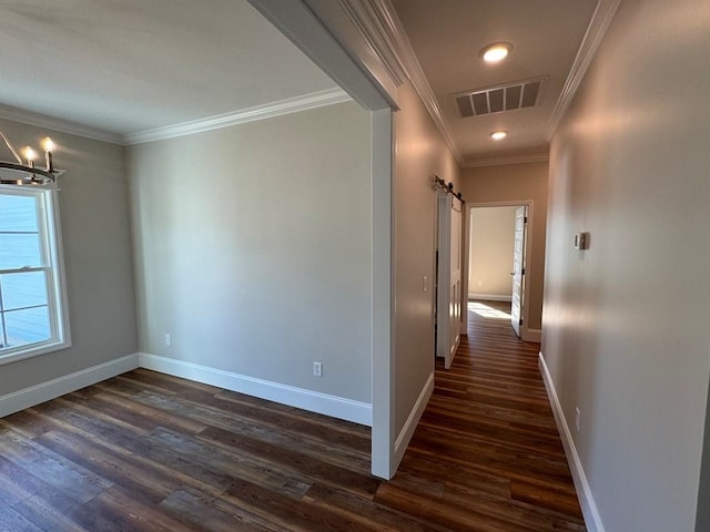 hallway featuring ornamental molding, a barn door, dark hardwood / wood-style floors, and an inviting chandelier