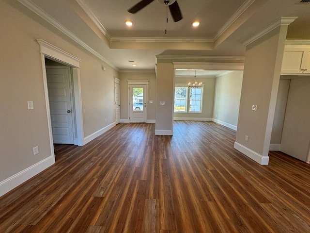 unfurnished living room featuring dark wood-type flooring, ornamental molding, and ceiling fan with notable chandelier