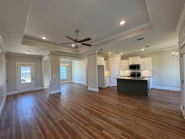 kitchen with a kitchen island with sink, dark wood-type flooring, ornamental molding, and white cabinets