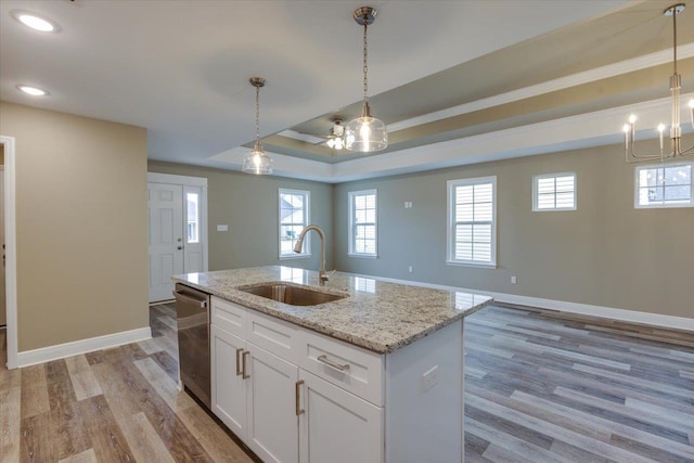 kitchen with sink, white cabinets, a kitchen island with sink, stainless steel dishwasher, and a tray ceiling